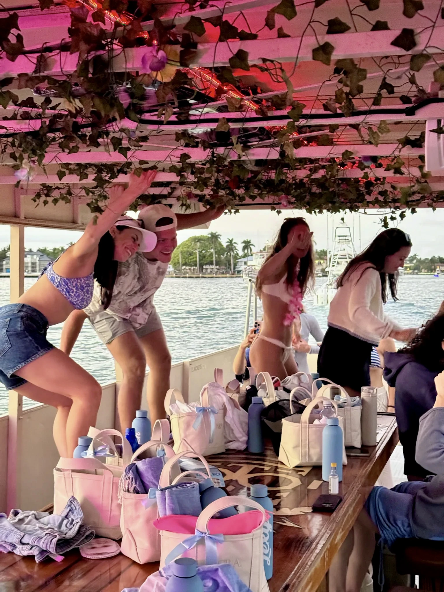 Bachelorette party guests dancing beside the Freaky Tiki table under pink deck lights in Fort Lauderdale