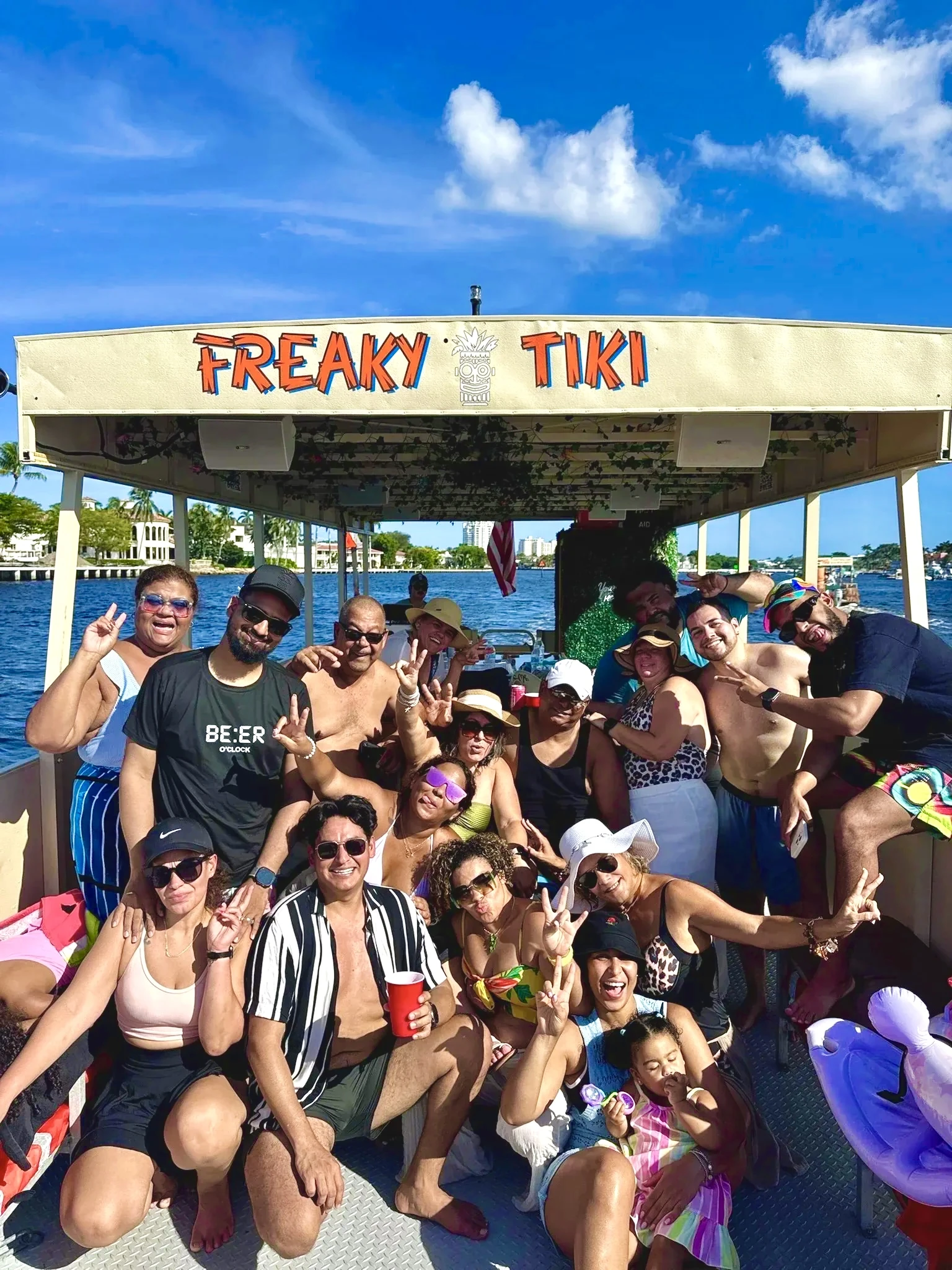 Multi-generation family group posing with a child beneath the Freaky Tiki sign in Fort Lauderdale